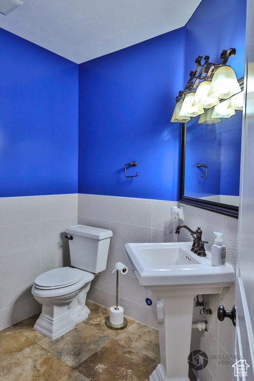 Bathroom with toilet, tile walls, and wainscoting