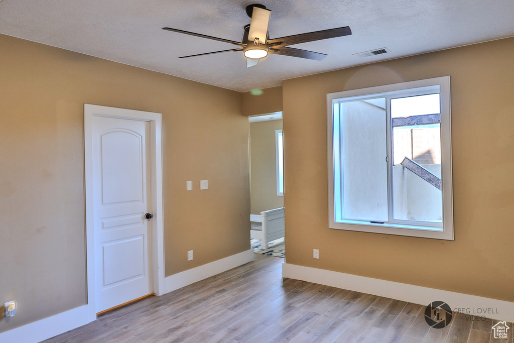 Spare room with light wood-style flooring, ceiling fan, and baseboards