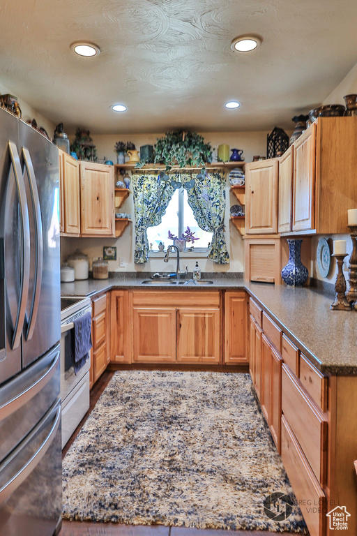 Kitchen featuring stainless steel appliances, a sink, open shelves, recessed lighting, and dark stone counters