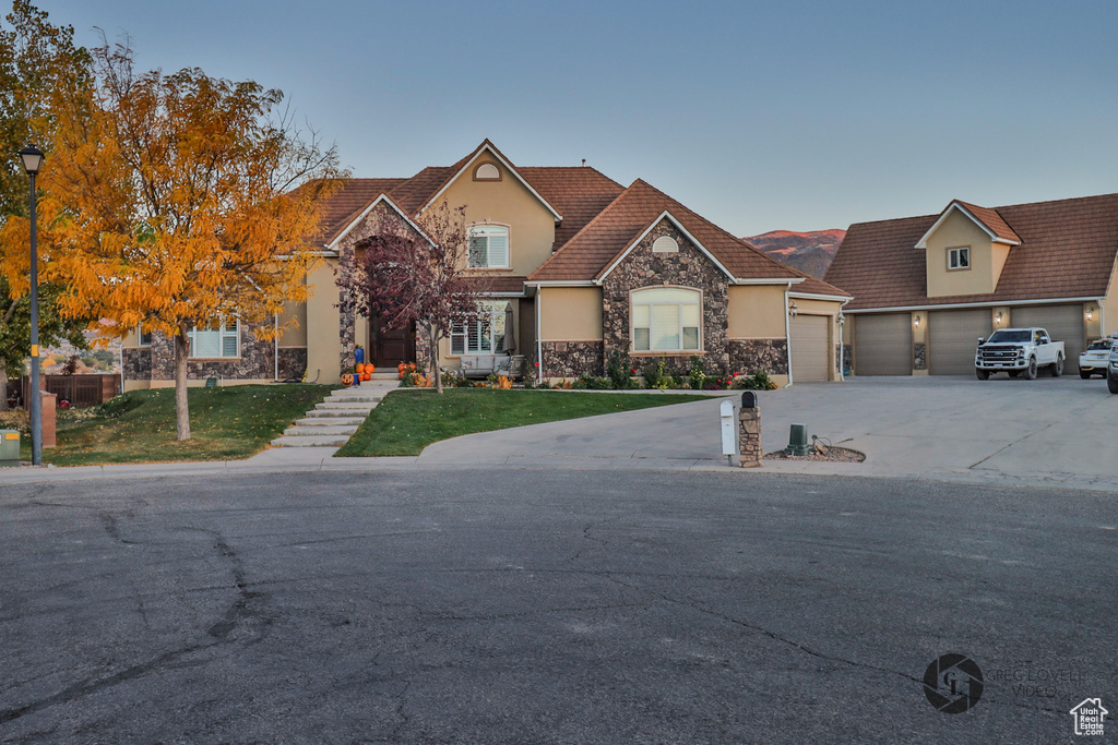 View of front of house with stone siding, stucco siding, concrete driveway, a front yard, and a garage