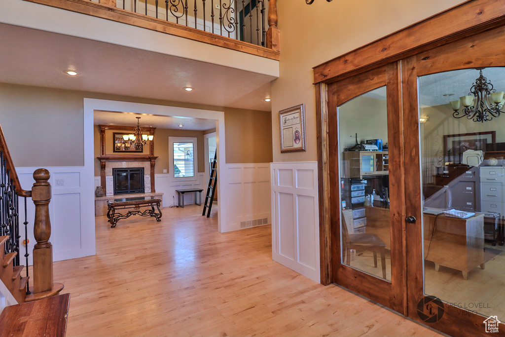 Entryway with a chandelier, a decorative wall, stairs, light wood finished floors, and a wainscoted wall