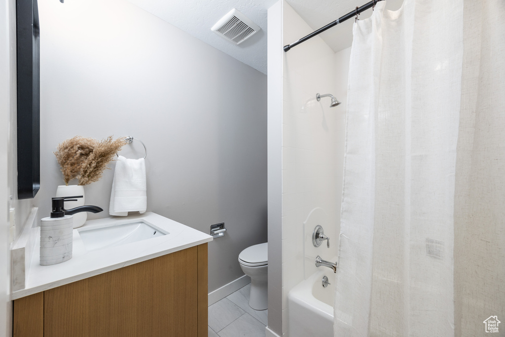 Full bath featuring toilet, vanity, tile patterned floors, shower / bath combo, and baseboards