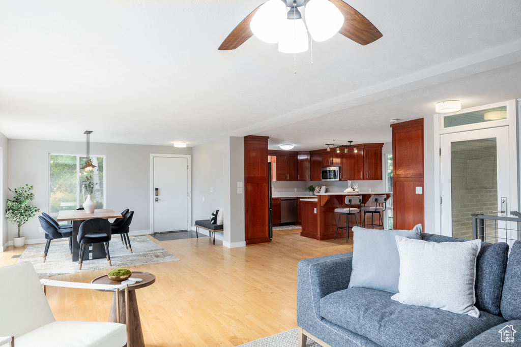Living room featuring light wood finished floors, a ceiling fan, and baseboards