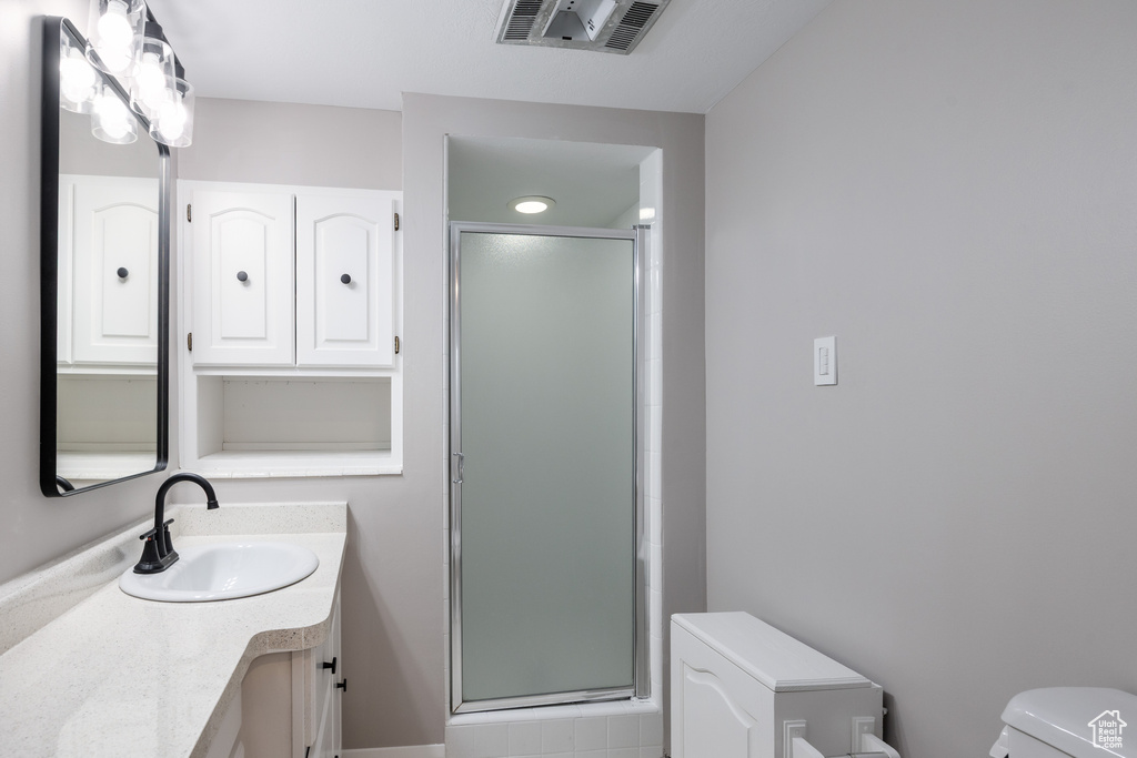 Bathroom featuring toilet, vanity, and a shower stall