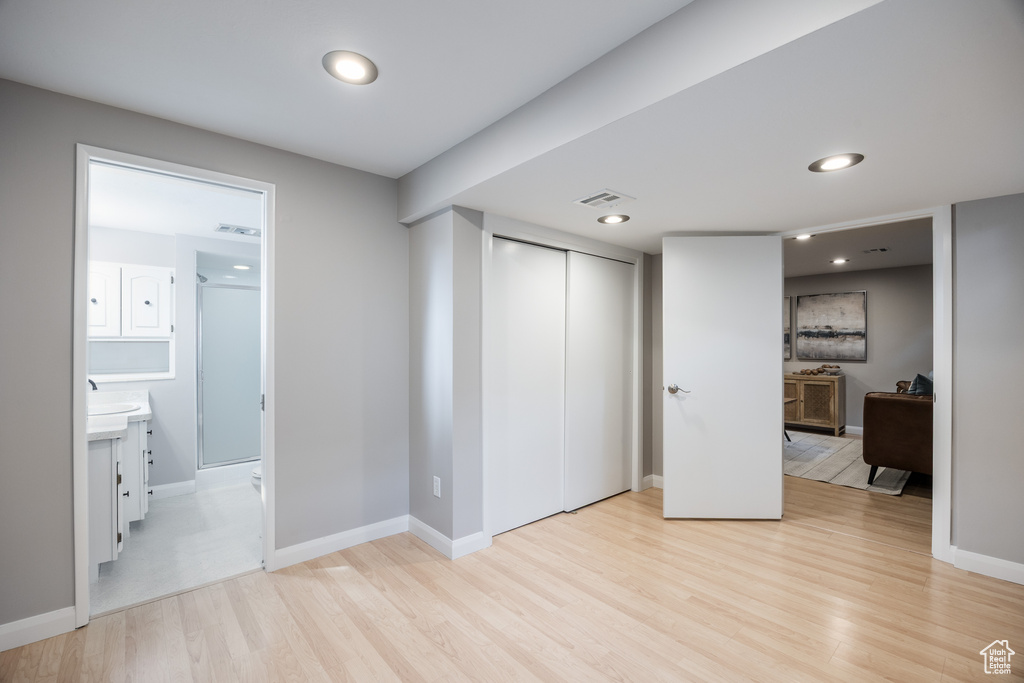 Unfurnished bedroom with light wood-type flooring, baseboards, a closet, connected bathroom, and recessed lighting