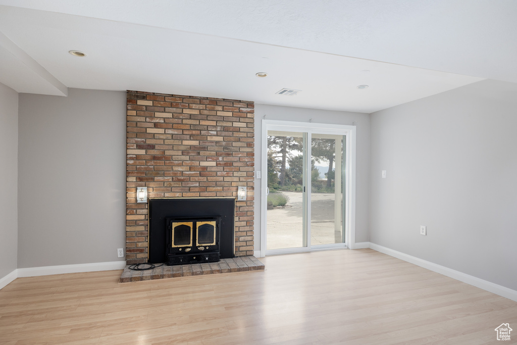 Unfurnished living room featuring wood finished floors, baseboards, a brick fireplace, and recessed lighting
