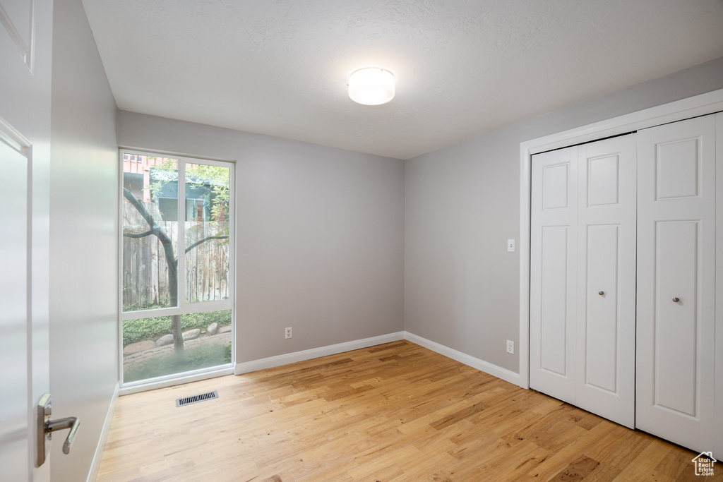 Unfurnished bedroom with light wood-type flooring, baseboards, access to exterior, and a closet