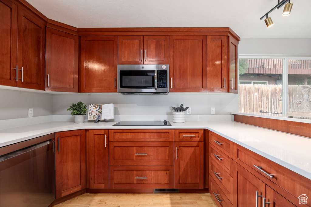Kitchen featuring stainless steel appliances, light wood finished floors, light countertops, and brown cabinets