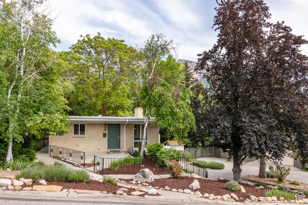 View of front of house featuring brick siding, a chimney, a fenced front yard, a porch, and driveway