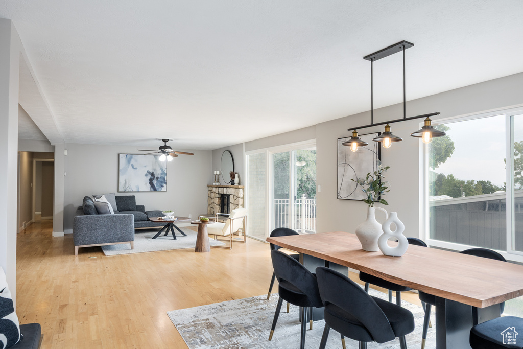 Dining room featuring a ceiling fan, light wood-type flooring, a fireplace, and baseboards