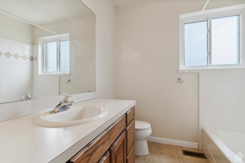 Bathroom with vanity, toilet, baseboards, and tile patterned floors