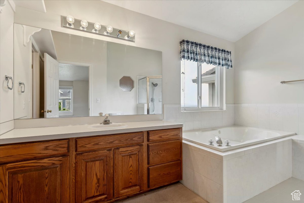 Bathroom featuring vanity, a bath, and a shower stall