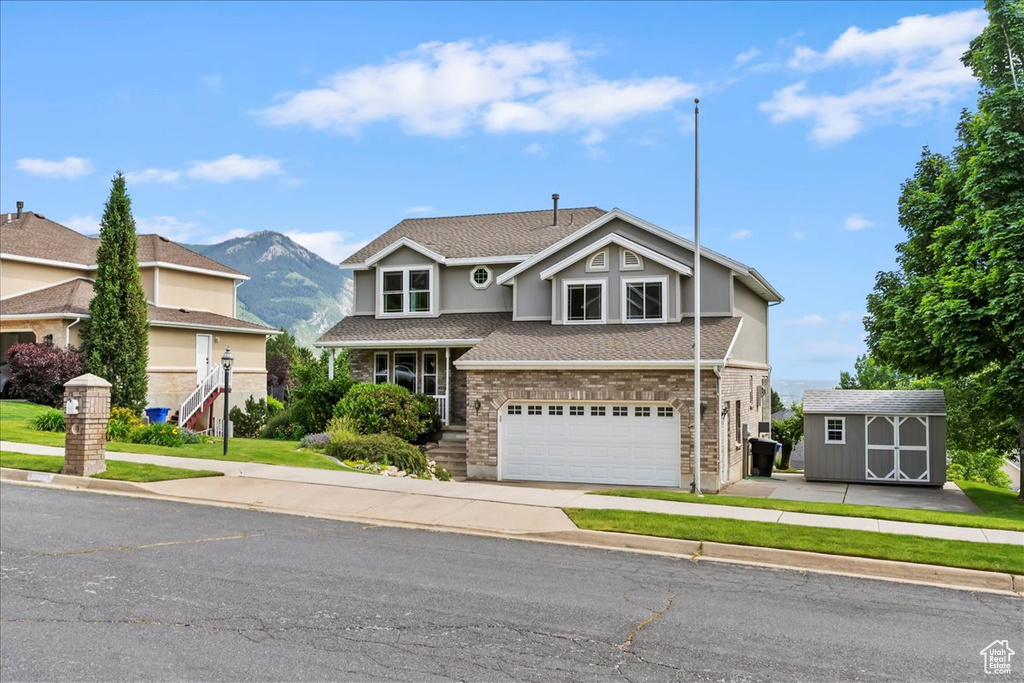 Traditional-style house featuring an attached garage, a shingled roof, a mountain view, concrete driveway, and stucco siding