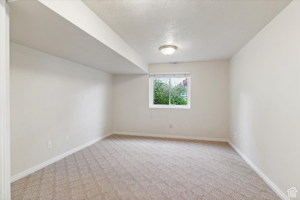 Carpeted spare room featuring baseboards and a textured ceiling
