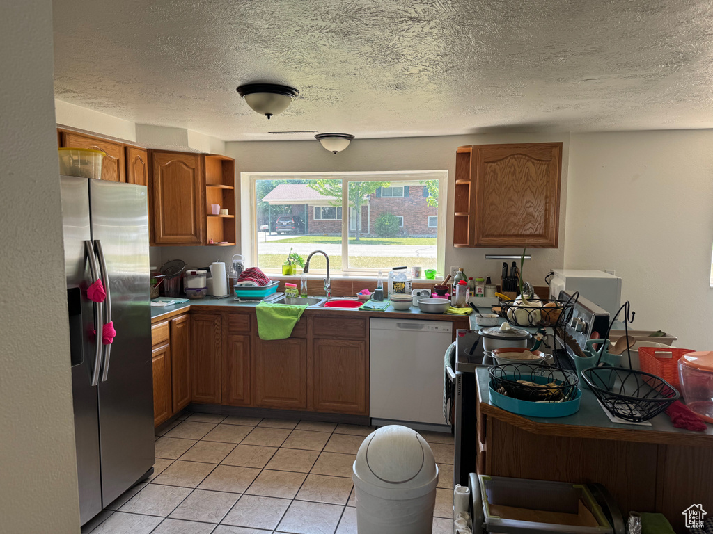 Kitchen featuring stainless steel fridge with ice dispenser, white dishwasher, open shelves, a sink, and brown cabinetry