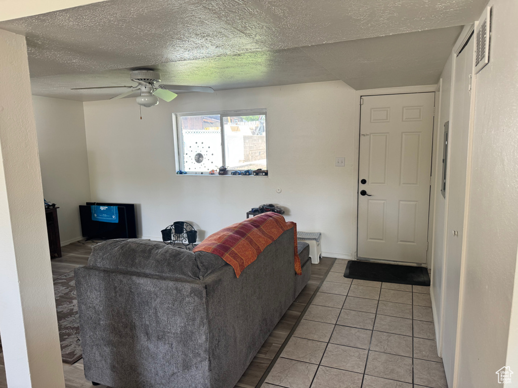 Living room with a ceiling fan, a textured ceiling, and light tile patterned flooring