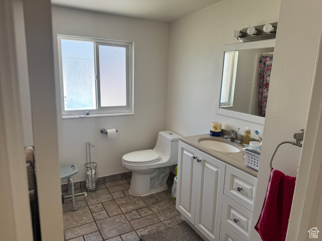 Full bath with vanity, toilet, and stone tile floors