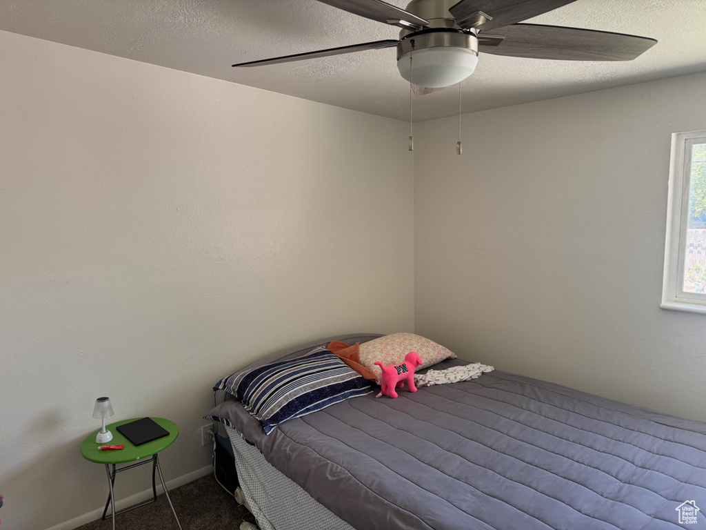 Carpeted bedroom with a ceiling fan and a textured ceiling