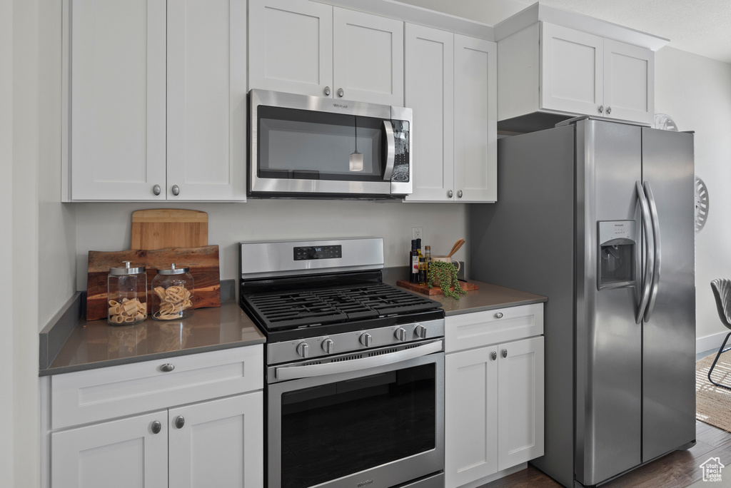 Kitchen with appliances with stainless steel finishes, white cabinetry, and dark wood-style flooring