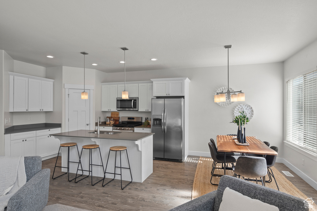Kitchen with appliances with stainless steel finishes, a sink, dark countertops, dark wood-style floors, and a chandelier
