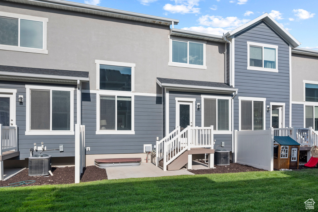 Back of house with central AC unit, a lawn, and stucco siding