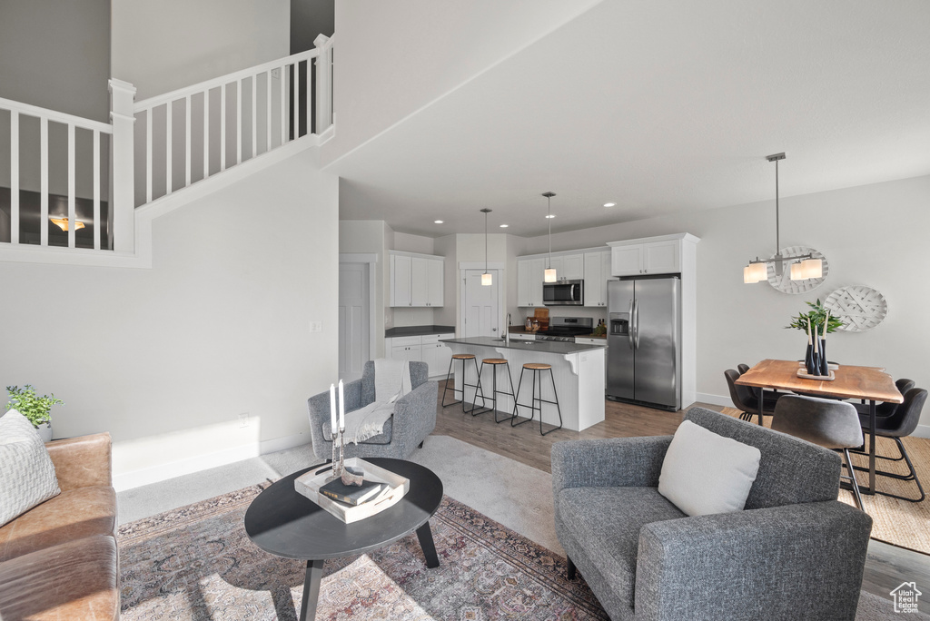 Living room with wood finished floors, recessed lighting, a chandelier, and stairway