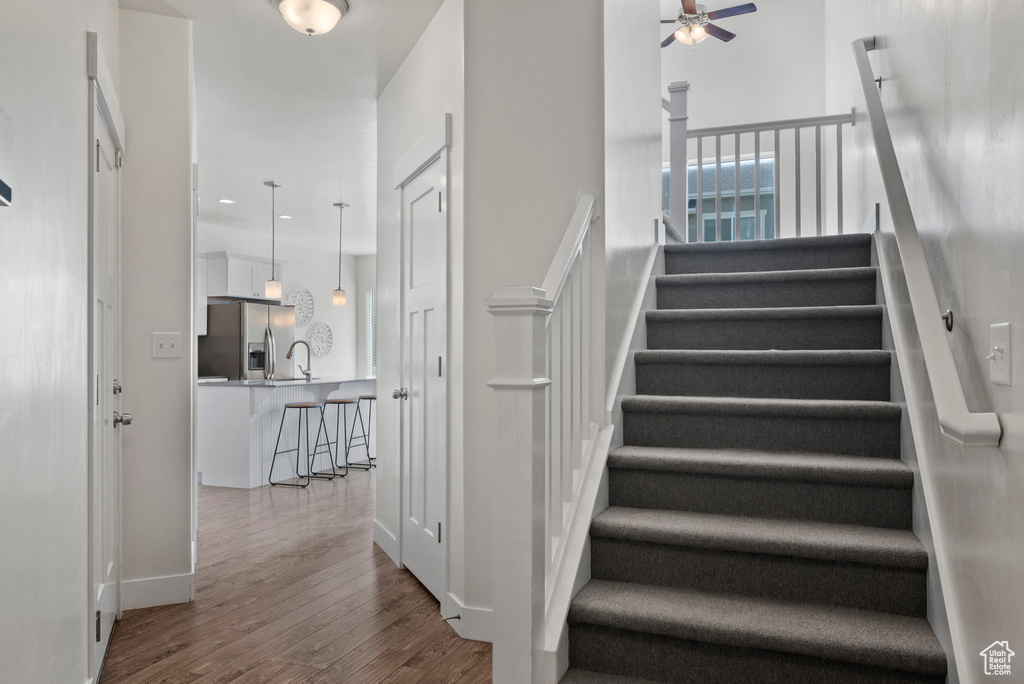 Staircase featuring ceiling fan, wood finished floors, baseboards, and recessed lighting