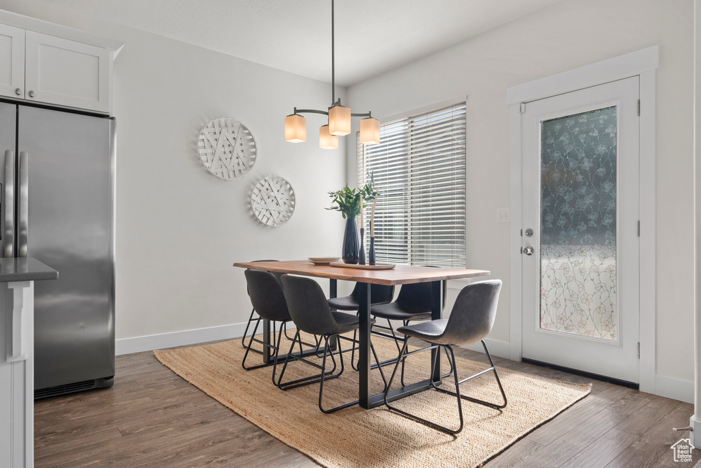Dining room with dark wood-style floors, baseboards, and a chandelier