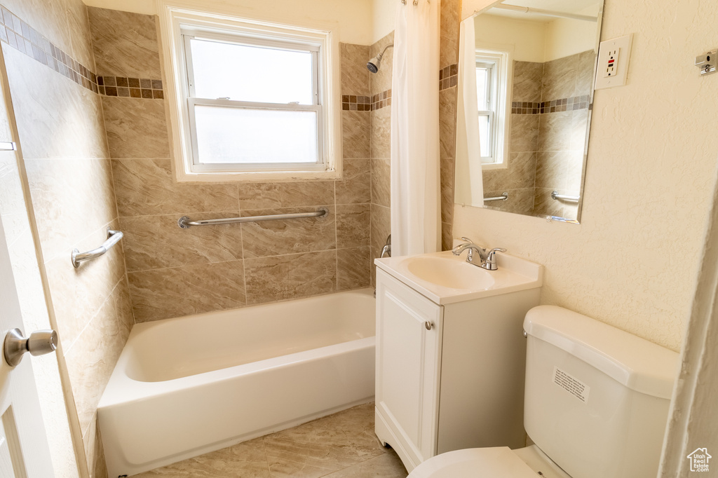 Bathroom featuring toilet, vanity, shower / bath combination with curtain, and plenty of natural light