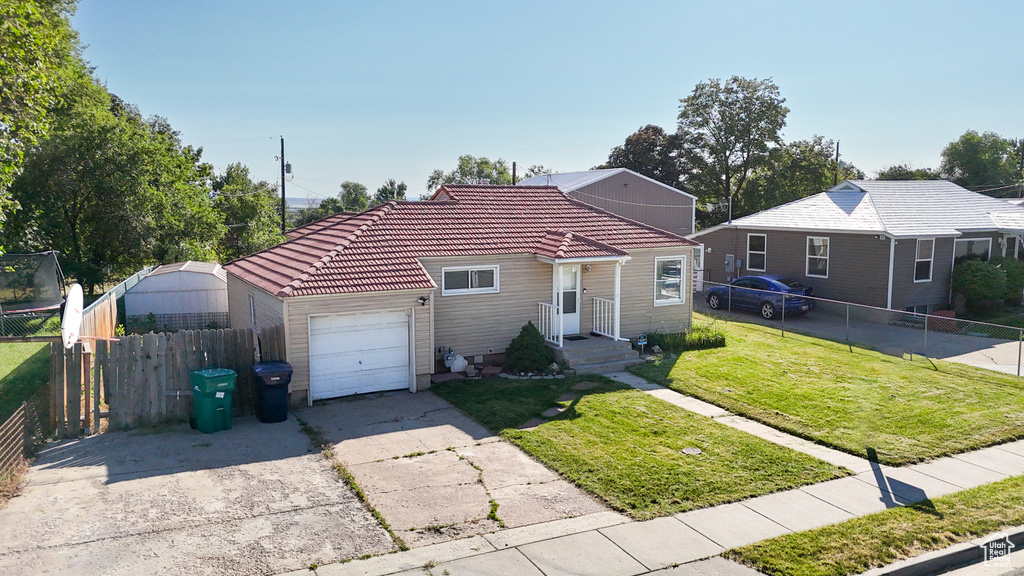 View of front of house with an attached garage, a tile roof, and driveway