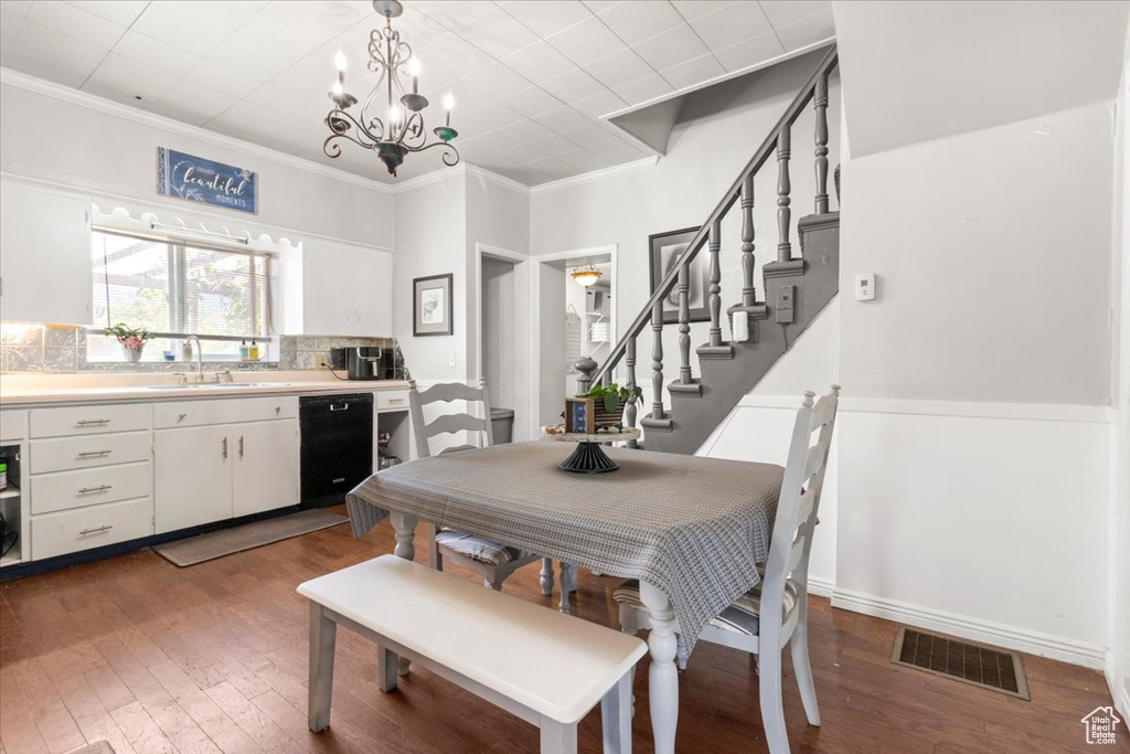 Dining space featuring wood finished floors, crown molding, a chandelier, and stairway