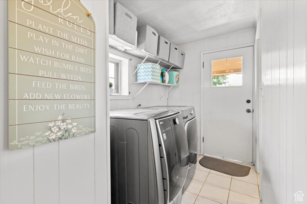 Laundry area featuring washing machine and dryer, light tile patterned flooring, and a textured ceiling