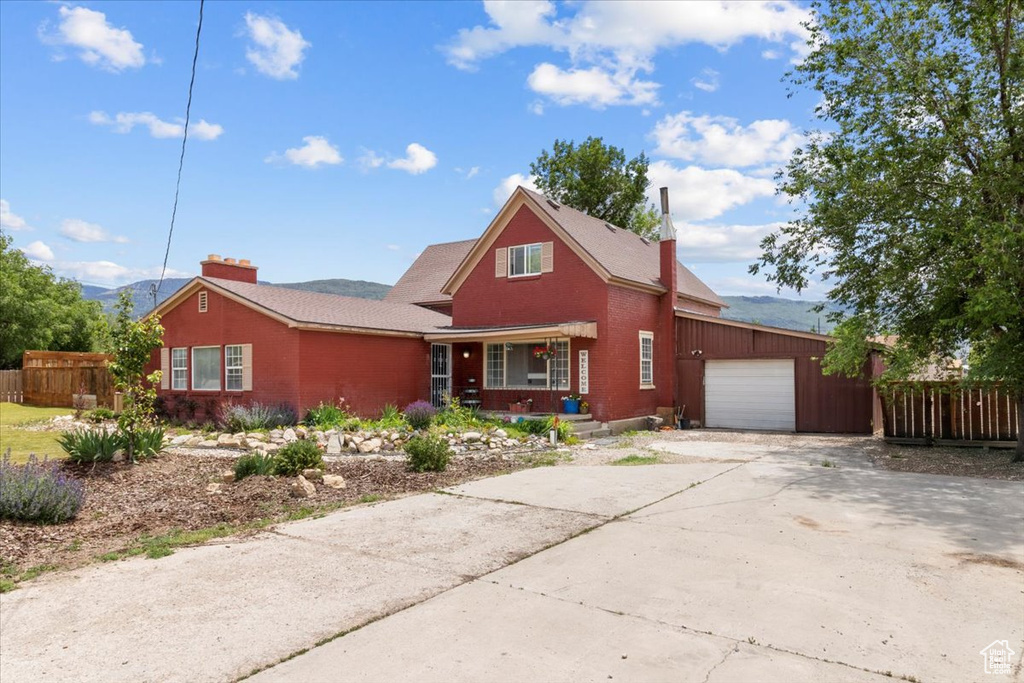View of front facade featuring a porch, a garage, concrete driveway, a chimney, and brick siding