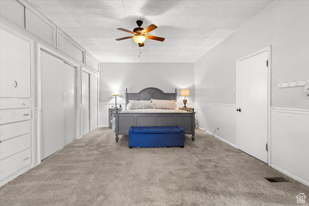Carpeted bedroom with a ceiling fan