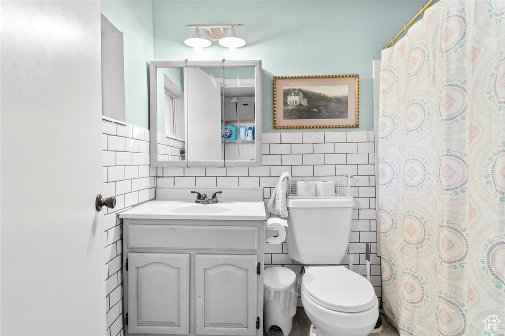 Full bathroom with tile walls, toilet, vanity, backsplash, and a shower with shower curtain