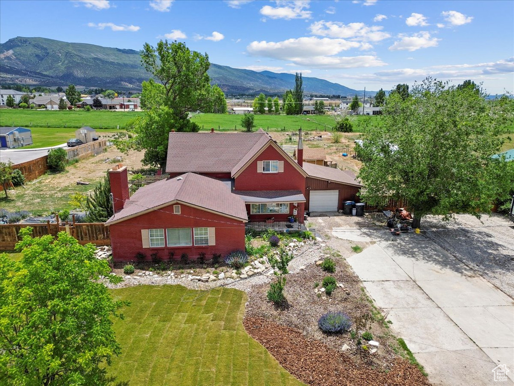 View of front of house with concrete driveway, a mountain view, and a garage