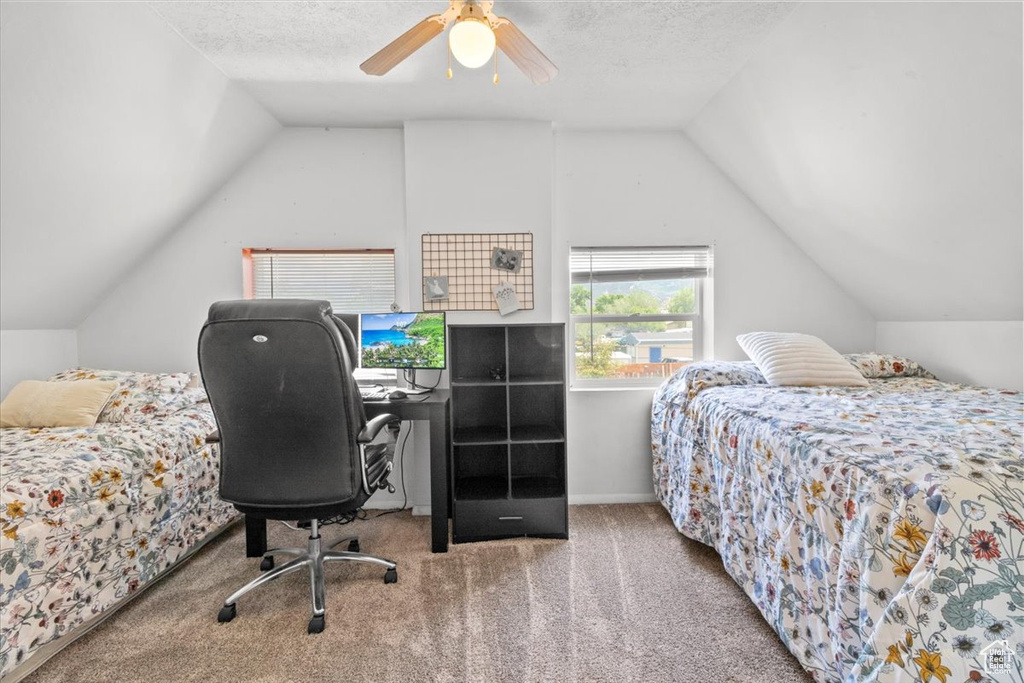 Carpeted bedroom with vaulted ceiling, a ceiling fan, and baseboards