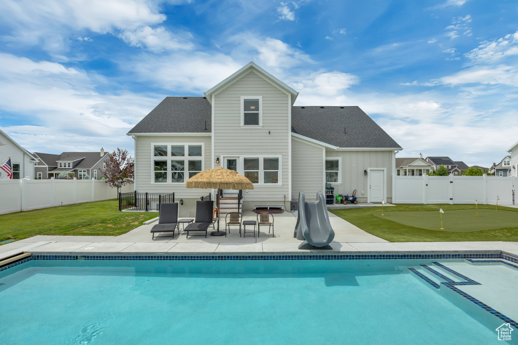 Back of property with an area to practice putting, a patio, board and batten siding, and a shingled roof