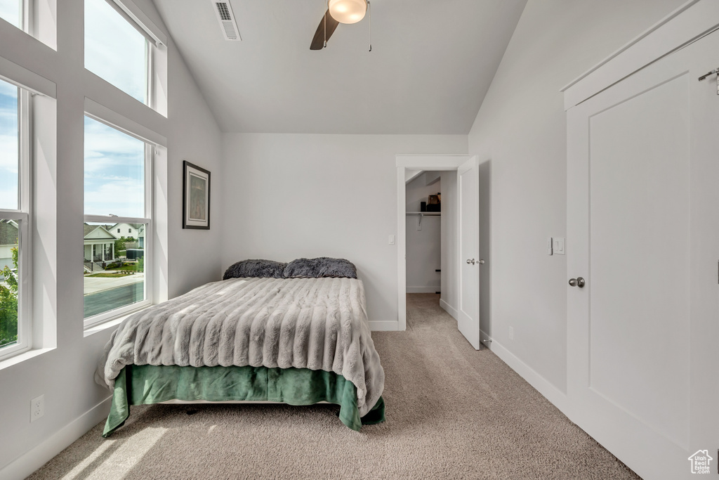 Bedroom featuring vaulted ceiling, multiple windows, light carpet, and ceiling fan