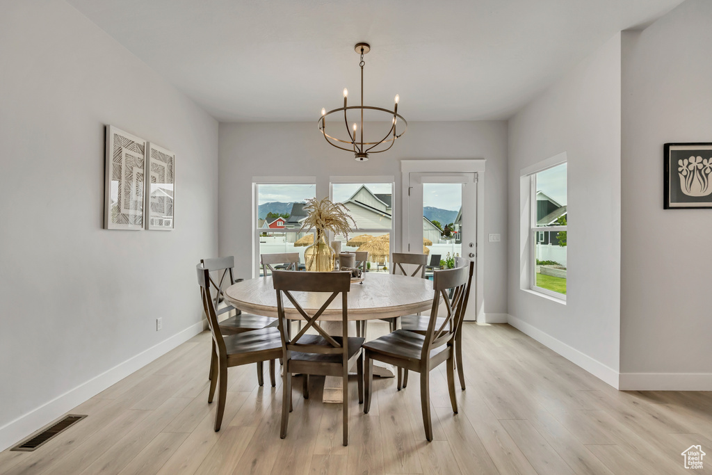 Dining space with light wood finished floors, a chandelier, and baseboards