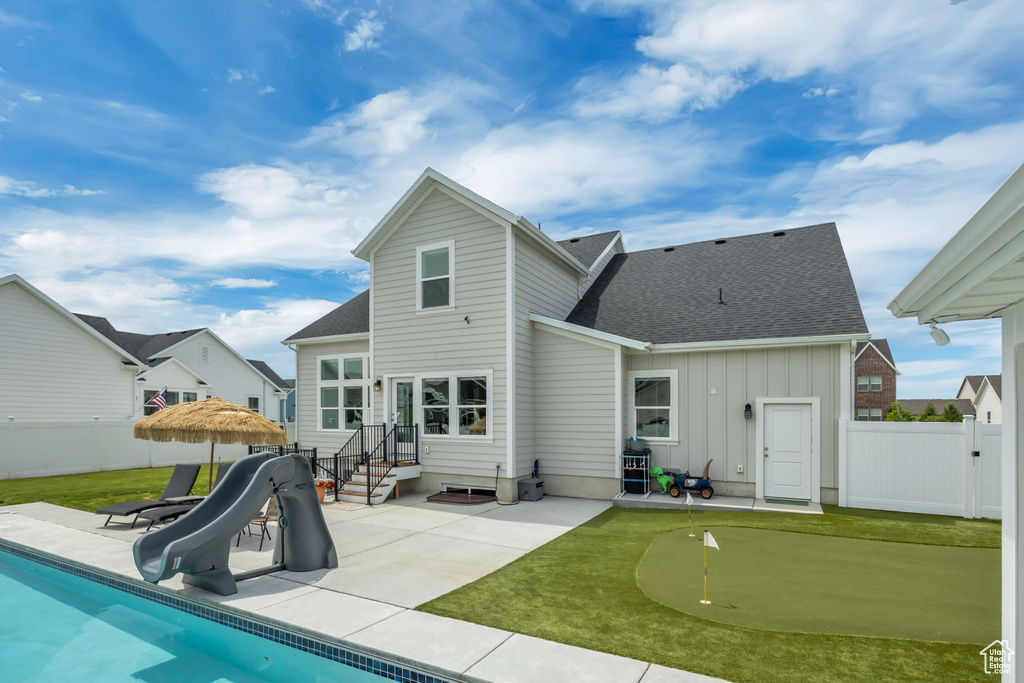 Back of house featuring a putting green, a patio area, board and batten siding, a fenced backyard, and a shingled roof