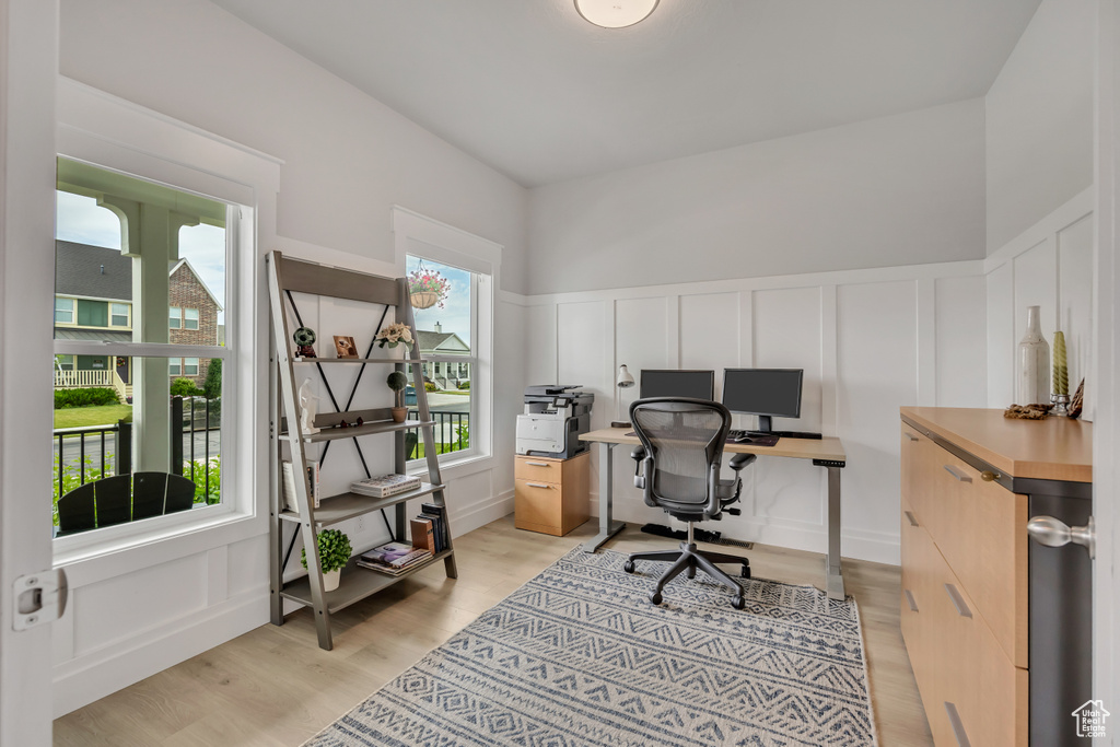 Office with a decorative wall, light wood-style flooring, and wainscoting