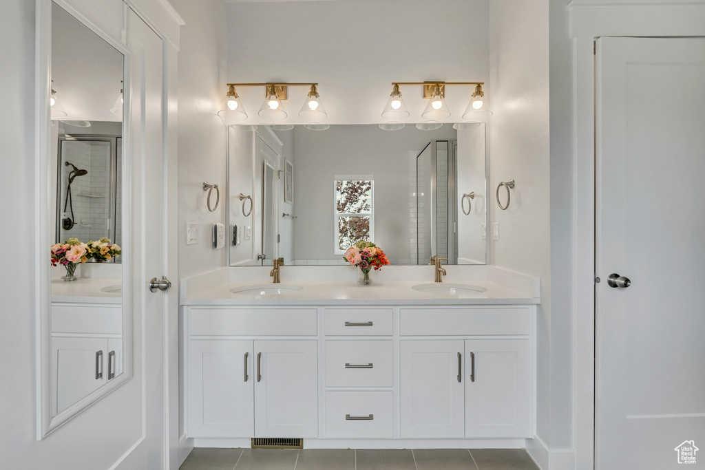 Full bathroom with a stall shower, double vanity, and tile patterned flooring