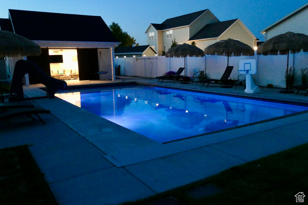 View of pool with a fenced backyard, a water slide, and a patio area