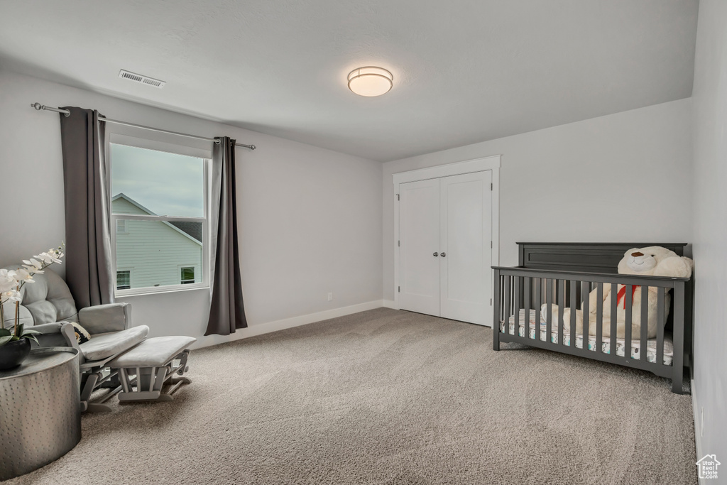 Carpeted bedroom featuring a closet, baseboards, and a nursery area