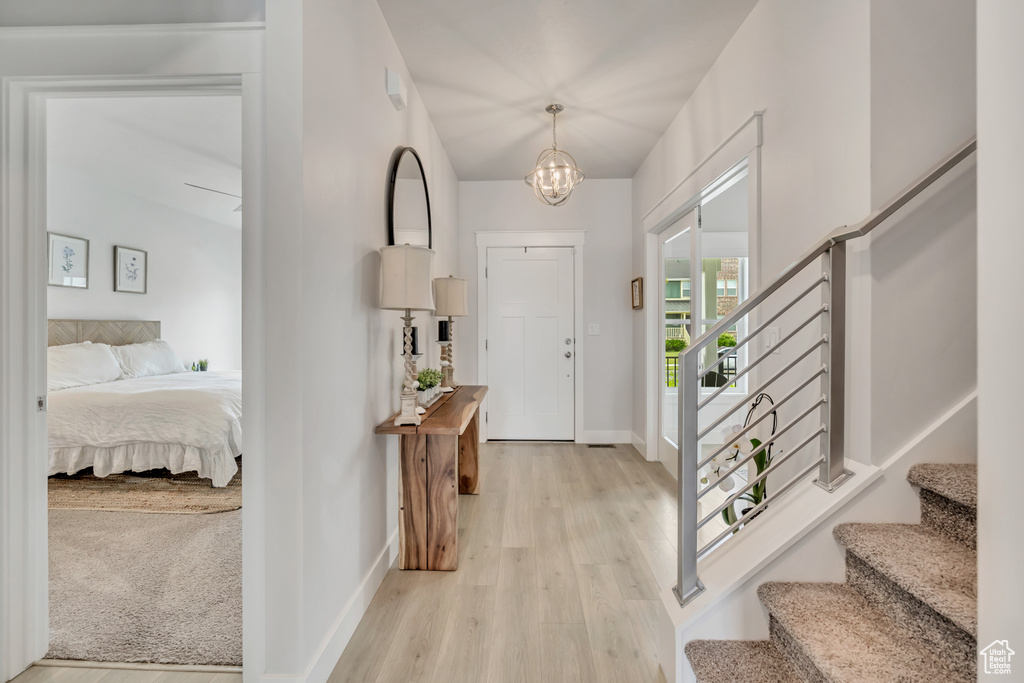 Foyer entrance with stairs, baseboards, light wood-type flooring, and a chandelier