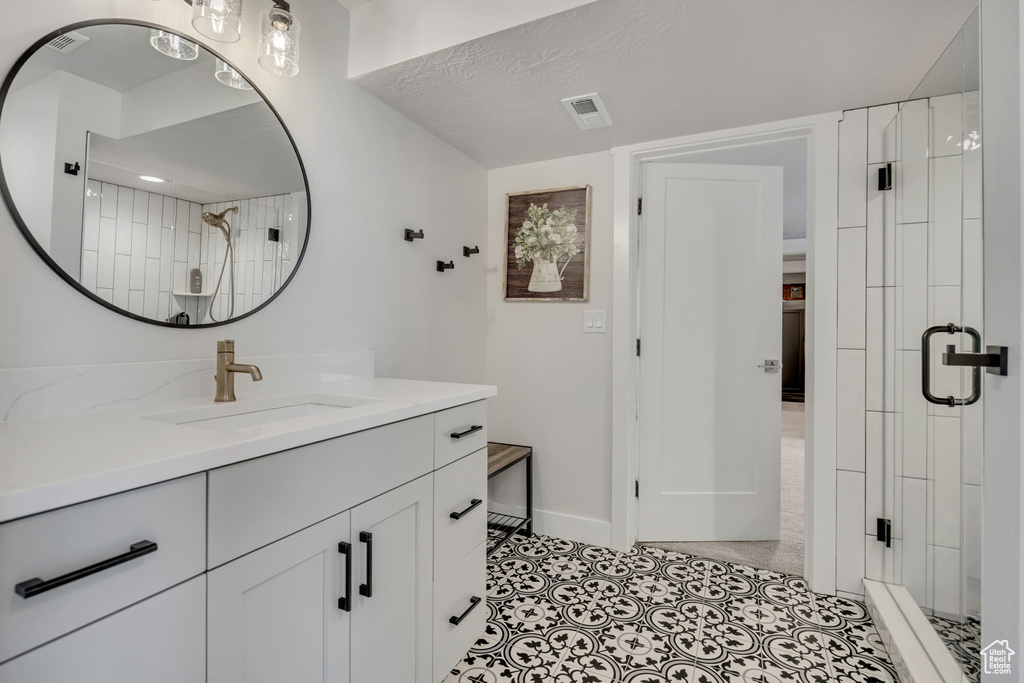 Bathroom featuring a shower stall, vanity, and baseboards