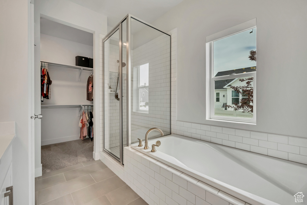 Full bath with a shower stall, a bath, tile patterned floors, a spacious closet, and healthy amount of natural light
