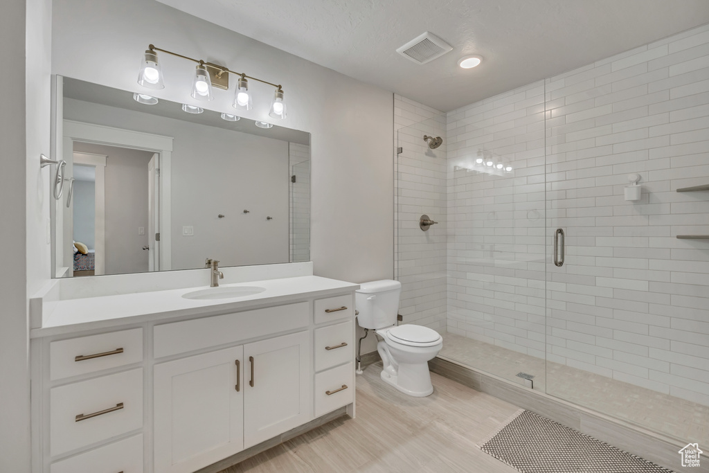 Full bath with vanity, toilet, a shower stall, and wood finished floors