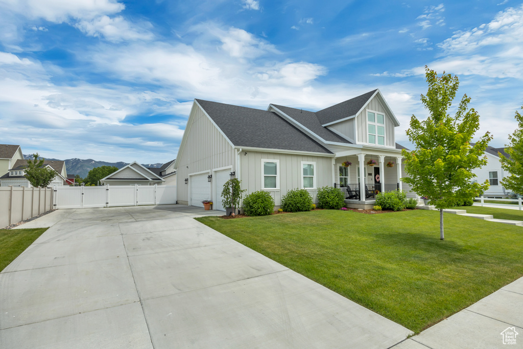 View of front of house featuring a gate, board and batten siding, covered porch, concrete driveway, and an attached garage